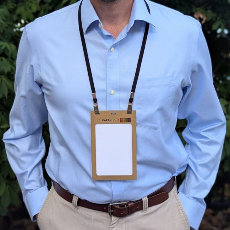 Man wearing recycled and recyclable kraft paper badge holder 4.25 x 6 with salvaged fabric rental lanyard made in USA