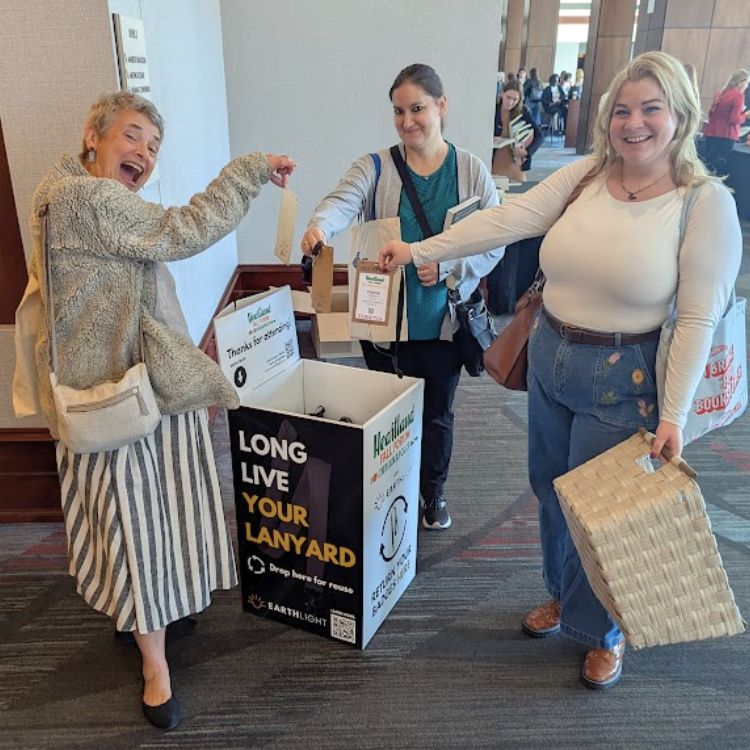 Three attendees dropping eco-friendly, rental lanyards back into event floor-standing lanyard and badge collection box