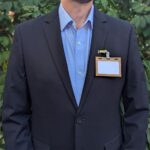 Person wearing reusable, plastic-free wood 3.5" x 2.25" name tag holder made in the USA with reusable metal double clip