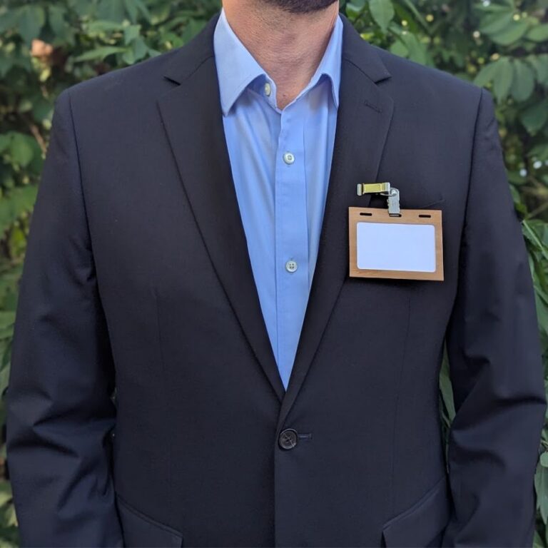 Person wearing reusable, plastic-free wood 3.5" x 2.25" name tag holder made in the USA with reusable metal double clip
